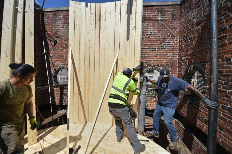 Workers with Isseks Brothers install a water tank atop a building on New York's Lexington Avenue