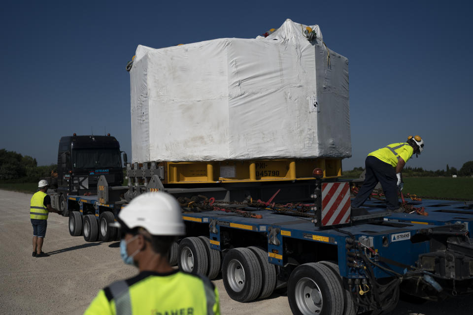 Workers secure a central solenoid magnet for the ITER project as it departs from Berre-l'Etang in southern France, Monday, Sept. 6, 2021. The first part of a massive magnet so strong its American manufacturer claims it can lift an aircraft carrier arrived Thursday, Sept. 9, 2021 at a high-security site in southern France, where scientists hope it will help them build a 'sun on earth.' Almost 60-feet tall and 14 feet in diameter when fully assembled, the magnet is a crucial component of the International Thermonuclear Experimental Reactor, or ITER, a 35-nation effort to develop an abundant and safe source of nuclear energy for future generations. (AP Photo/Daniel Cole)