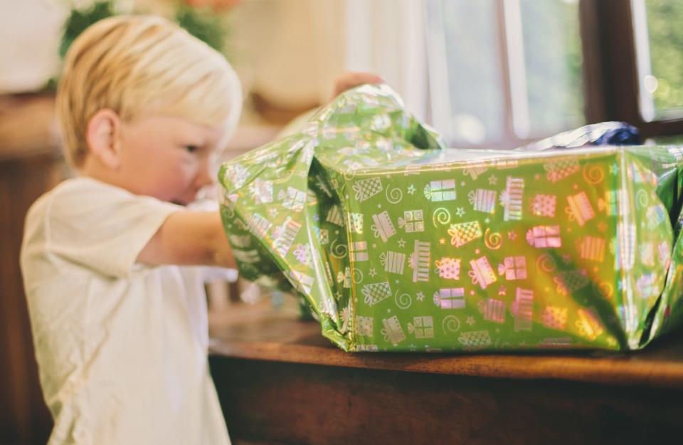 a little boy digs through a birthday box as he unwraps it