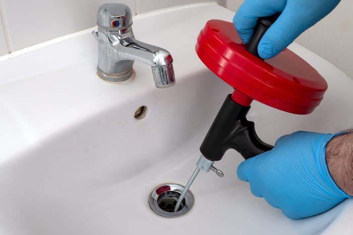 plumber using a snake to unclog bathroom sink drain