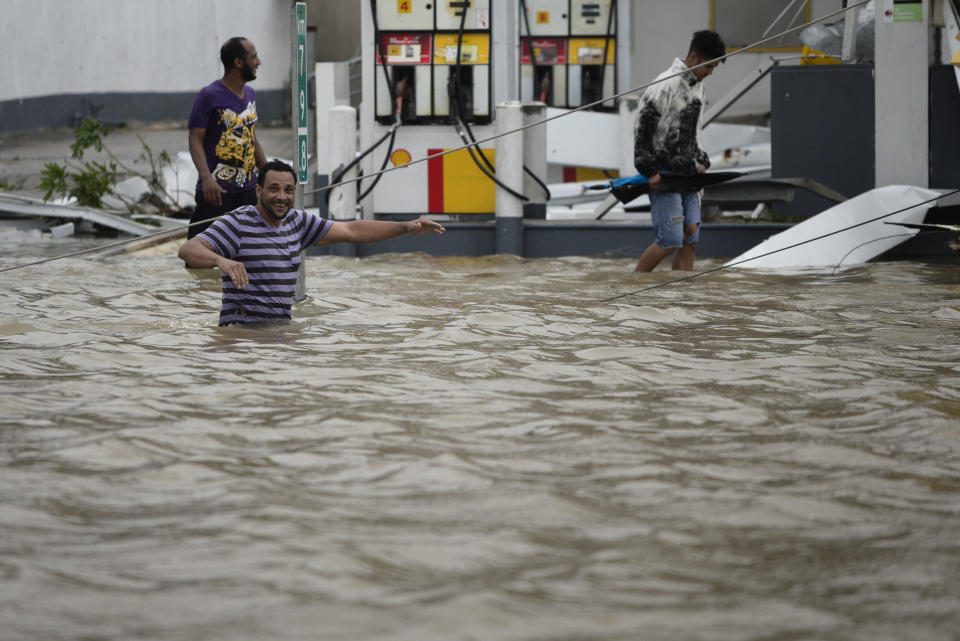 <p>People walk next to a gas station flooded and damaged by the impact of Hurricane Maria, which hit the eastern region of the island, in Humacao, Puerto Rico, Wednesday, September 20, 2017. (Photo: Carlos Giusti/AP) </p>