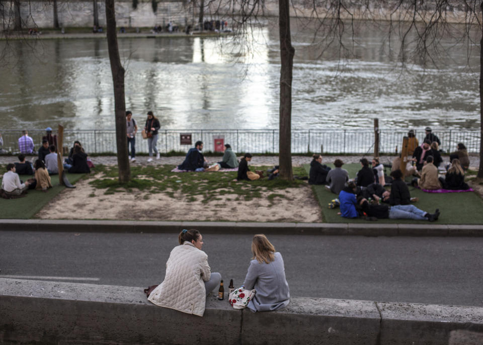 People stroll along the Seine river banks at sunset Sunday March 15, 2020 in Paris.  (AP Photo/Rafael Yaghobzadeh)