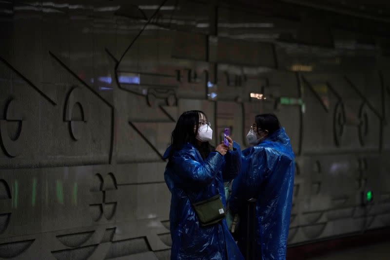 Women wear masks and plastics rain coat as protection from coronavirus at a subway station in Shanghai