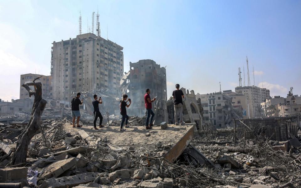 People survey the damage from Israeli air strikes in the Al-Rimal neighborhood of Gaza City on Tuesday