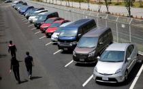 FILE PHOTO: People walk beside test-driving cars outside a car maker's showroom in Tokyo