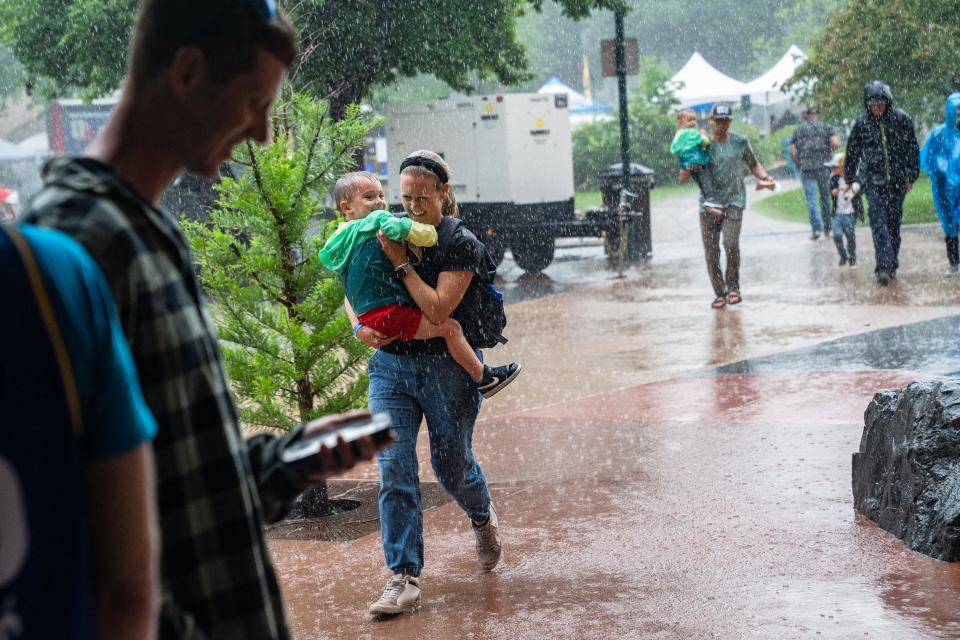 People run toward shelter during a heavy rainstorm at Taste of Fort Collins on Sunday. The event was canceled in the early evening due to severe weather.