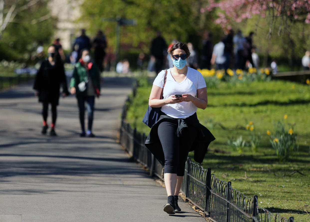 A woman wearing protective face masks enjoys the warm weather at Regent’s Park, North London, as the UK continues in lockdown to help curb the spread of the coronavirus