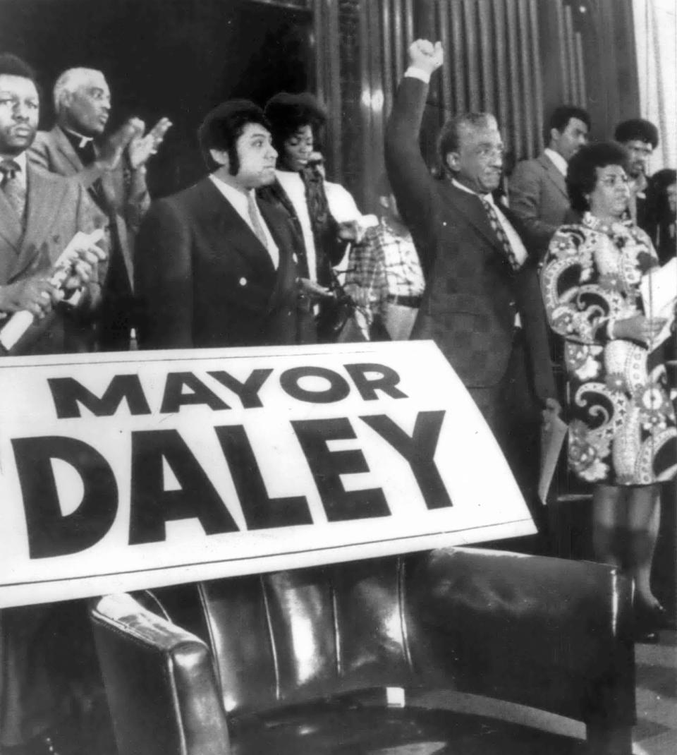 "It's never too late to be Black, it's never too late," said Rep. Ralph Metcalfe, D-Ill. With her arm stretched high in the Black Power salute, Metcalfe stands behind an empty chair "Reserved" for Mayor Richard Daley at a Chicago southside meeting held to protest alleged police brutality in the Black community on May 31, 1972. Metcalfe, once a stanch supporter of Daley now said, "Mayor Daley is not God. I only worship God. I will not sell out my people."