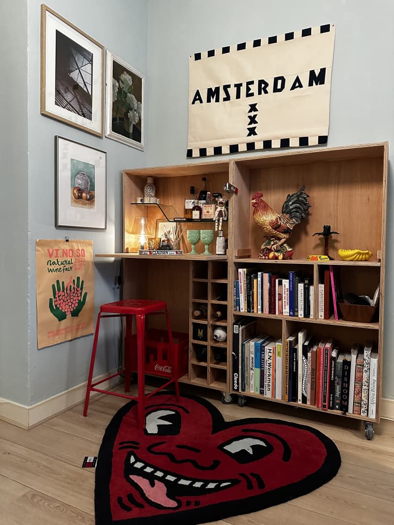 Corner with shelving, heart-shaped rug, and art on the wall that reads "Amsterdam"