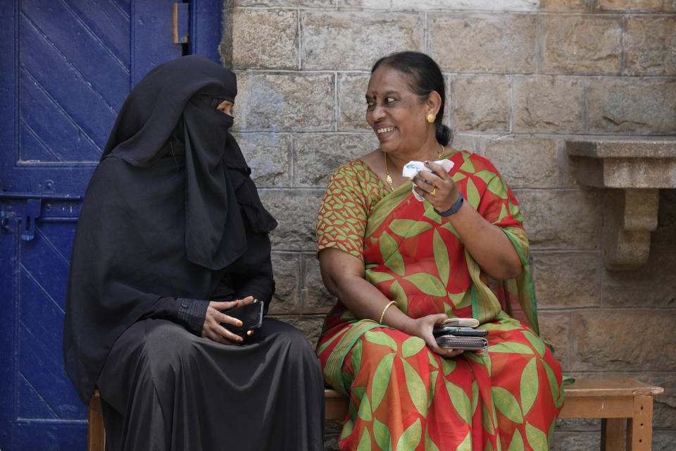 A Hindu woman, right, chats with a Muslim woman after casting their votes as they wait for their family members at a polling station in Bengaluru, India, Wednesday, May 10, 2023. People in the southern Indian state of Karnataka were voting Wednesday in an election where pre-poll surveys showed the opposition Congress party favored over Prime Minister Narendra Modi's governing Hindu nationalist party. (AP Photo/Aijaz Rahi)