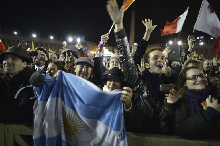 Members of the faithful wave an Argentinian flag as Argentina's cardinal Jorge Bergoglio, elected Pope Francis I (L) appears on the balcony of St Peter's Basilica's after being elected the 266th pope of the Roman Catholic Church on March 13, 2013 at the Vatican