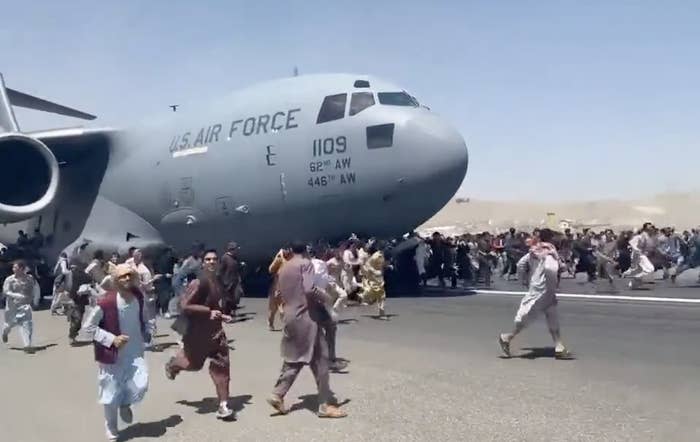 "People run on tarmac of Kabul international airport as a US military aircraft attempts to take off"