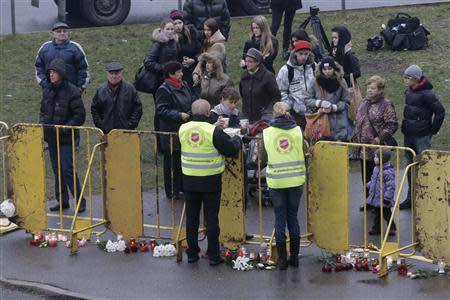 Volunteers serve drinks to people standing near a collapsed supermarket in Riga November 22, 2013. REUTERS/Ints Kalnins