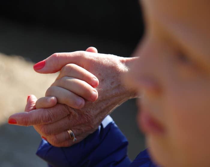 Photo of a young kid holding an older woman's hand