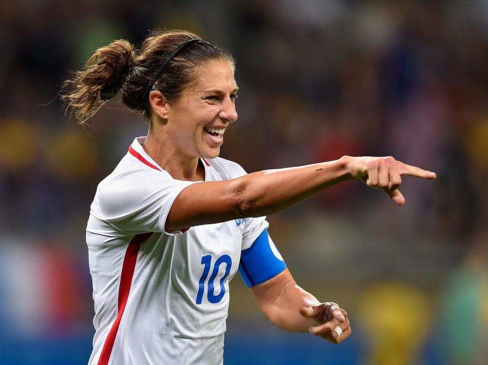 Carli Lloyd points and smiles during a game.