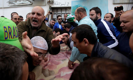 A relative reacts by the coffin of British-Algerian journalist Mohamed Tamalt, British-Algerian journalist who had died six months after staging a hunger strike in Algiers over his detention for publishing articles seen as offensive to President Abdelaziz Bouteflika, during his funeral in Algiers, Algeria December 12, 2016. REUTERS/ Ramzi Boudina