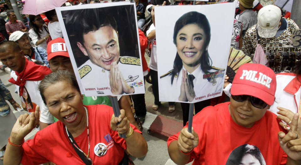 FILE - In this Aug. 5, 2011 file photo, supporters of Pheu Thai Party, holding portraits of former Thai Prime Minister Thaksin Shinawatra, left, and his sister Yingluck Shinawatra, cheer outside Parliament in Bangkok, Thailand. Yingluck marks a year in office this weekend as Thailand's first female prime minister. Her achievement is all the more remarkable because she is the sister of the man at the center of Thailand's long-running political maelstrom, who was deposed by a military coup in 2006 after being accused of corruption and disrespect for King Bhumibol Adulyadej. (AP Photo/Sakchai Lalit, File)