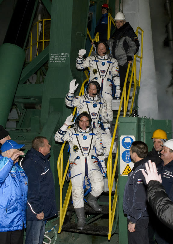 Expedition 39 Soyuz Commander Alexander Skvortsov of the Russian Federal Space Agency, Roscosmos, bottom, Flight Engineer Steve Swanson of NASA, middle, and Flight Engineer Oleg Artemyev of Roscosmos, wave farewell prior to boarding the Soyuz T