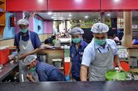 Staff members of the Indian Railway Catering and Tourism Corporation wear facemasks, as a preventive measure againsts the spread of the COVID-19 at Bangalore City Railway Station