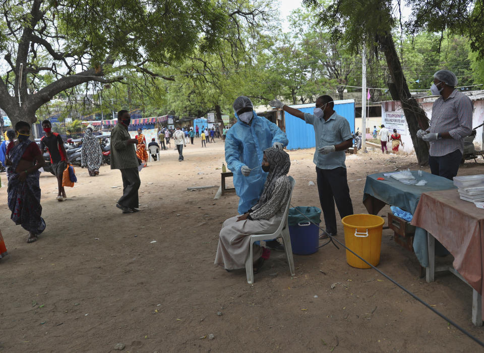 A health worker takes a nasal swab sample of a woman to test for COVID-19 in Hyderabad, India, Friday, May 7, 2021. With coronavirus cases surging to record levels, Indian Prime Minister Narendra Modi is facing growing pressure to impose a harsh nationwide lockdown amid a debate whether restrictions imposed by individual states are enough. (AP Photo /Mahesh Kumar A.)