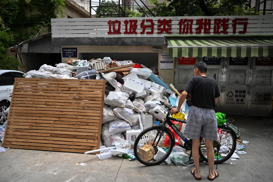 In this photo taken on July 11, 2019, a man looks at piled up garbage at a housing complex in the former French concession in Shanghai. - Shanghai on July 1 launched China's most ambitious garbage separation and recycling programme ever, as the country confronts a rising tide of trash created by increasingly consumptive ways. But the programme is the talk of China's biggest city for other reasons as well: confusion over rules and fines for infractions, and thousands of volunteers inspecting citizens' private garbage each day. (Photo by HECTOR RETAMAL / AFP) / TO GO WITH: China-environment-waste-recycling, FOCUS by Lianchao LAN and Dan MARTIN        (Photo credit should read HECTOR RETAMAL/AFP via Getty Images)