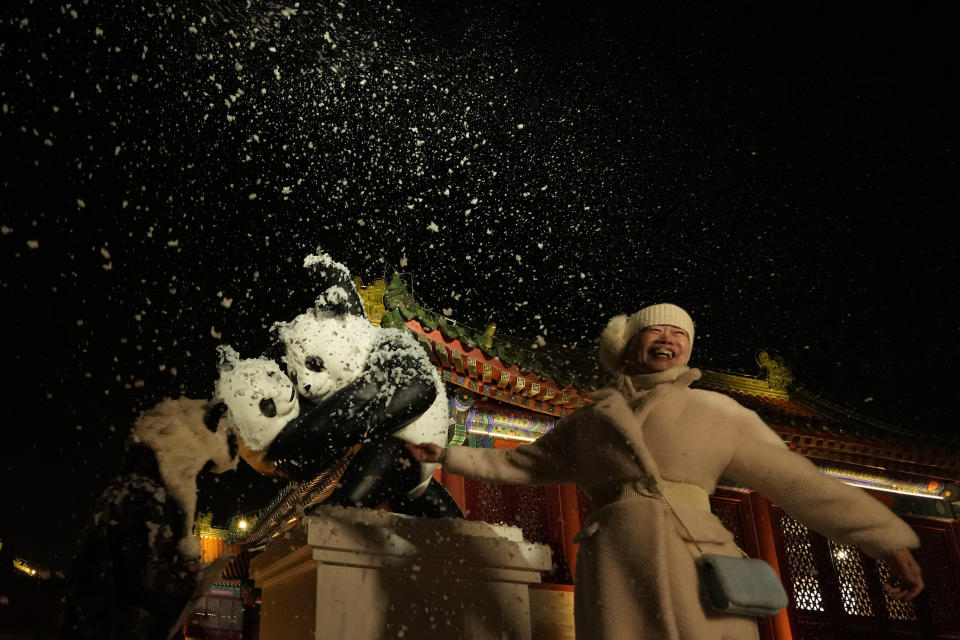 Una asistente a un evento que coincidió con la Nochevieja sonríe mientras sale nieve artificial de una máquina en Beijing, China, el viernes 31 de diciembre de 2021. (AP Foto/Ng Han Guan)