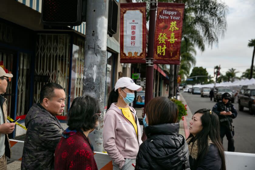 MONTEREY PARK, CA - JANUARY 22: Community members watch as officials secure and investigate the scene where a gunman opened fire at a ballroom dance studio in Monterey Park in Monterey Park in Monterey Park, CA. (Jason Armond / Los Angeles Times)