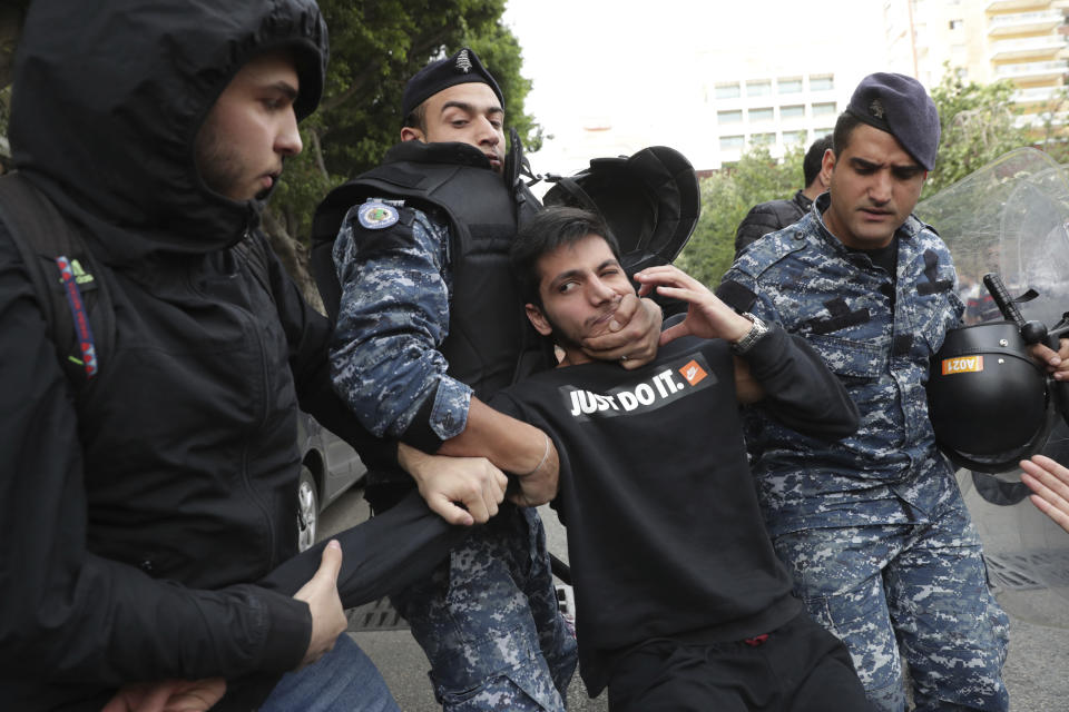 Riot police scuffle with anti-government protesters blocking a road in Beirut, Lebanon, Monday, Nov. 25, 2019. A key road has reopened in the Lebanese capital following clashes throughout the night between rival groups. (AP Photo/Hassan Ammar)