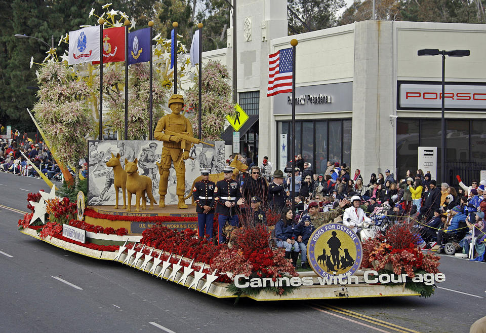 The Natural Balance Pet Foods float, "Canines With Courage," is the winner of the Past Presidents' trophy for the most innovative use and presentation of flowers, in the 124th Rose Parade in Pasadena, Calif., Tuesday, Jan. 1, 2013. Seated at the front are Army Sgt. First Class Eric Pazz, waving, and his wife Miriam and 4-year-old son Eric Jr. after their surprise reunion on the parade route. Miriam Pazz had been told she had won a contest to attend the parade and did not know her husband, who was deployed in Afghanistan, would be there. He got off the float in front of their seats, to a standing ovation on their reunion. (AP Photo/Reed Saxon)