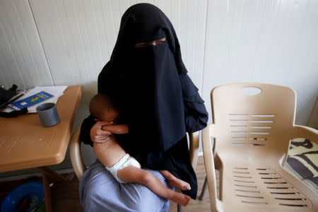 FILE PHOTO: Chechen woman Laila Magomedovna Gazieva, the widow of an Islamic State militant, holds her son Obaida at Hammam Al-Alil camp south of Mosul, Iraq, September 13, 2017. REUTERS/Azad Lashkari/File Photo