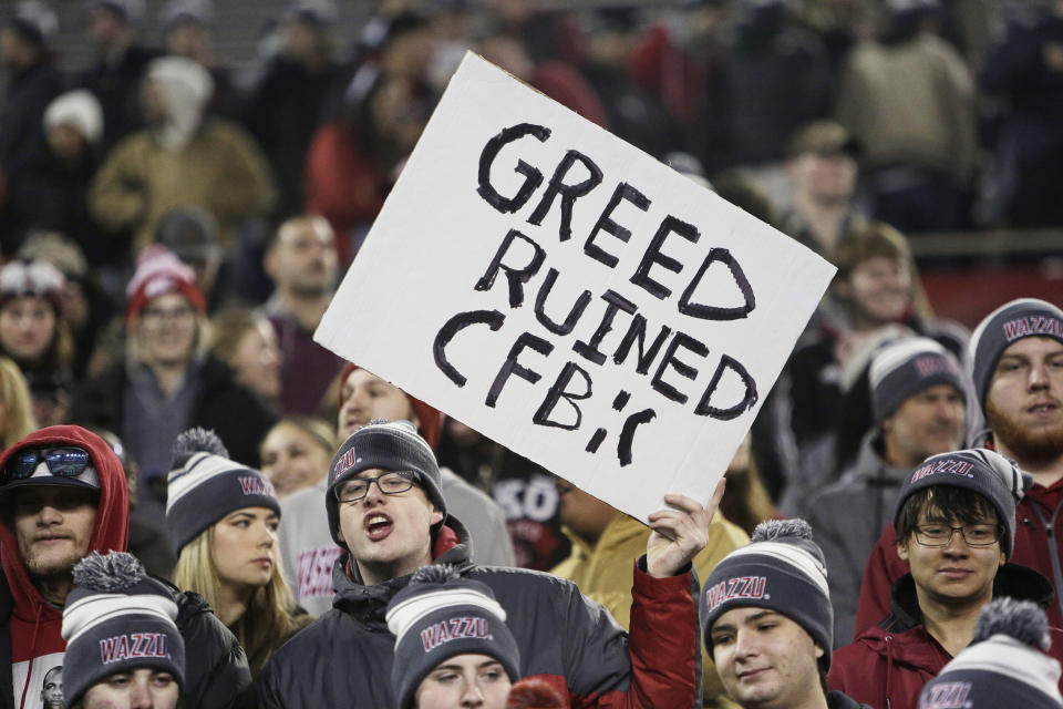 A Washington State fan holds a sign critical of college football before an NCAA college football game between Washington State and Colorado, Friday, Nov. 17, 2023, in Pullman, Wash. (AP Photo/Young Kwak)