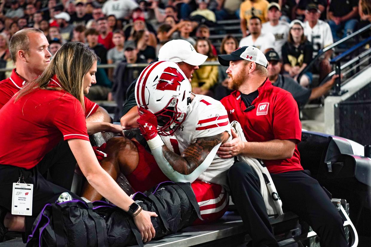 Badgers running back Chez Mellusi is taken off the field in a cart after suffering an injury against Purdue.