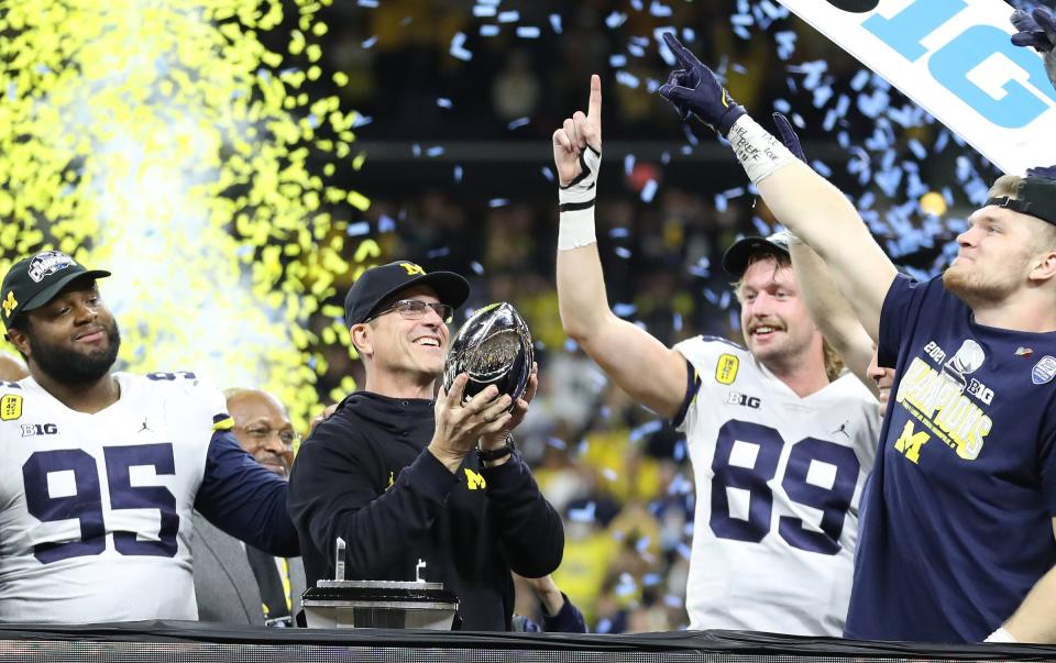 Michigan coach Jim Harbaugh raises the trophy after the Wolverines' 42-3 win over Iowa in the Big Ten championship game.