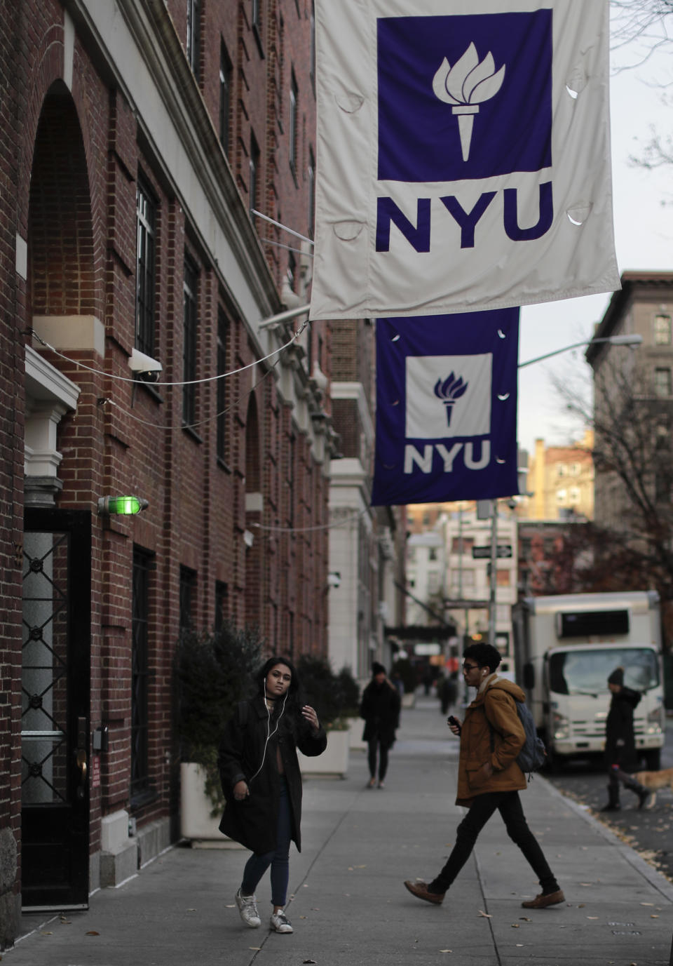 Students walk along Washington Square West in front of New York University's Lipton Hall, Wednesday, Dec. 14, 2016, in New York. New York University has introduced a program to help students save money by putting them up in elderly people's spare bedrooms. The plan has gotten serious consideration from some students straining under the institution's $66,000 annual tuition. (AP Photo/Julie Jacobson)