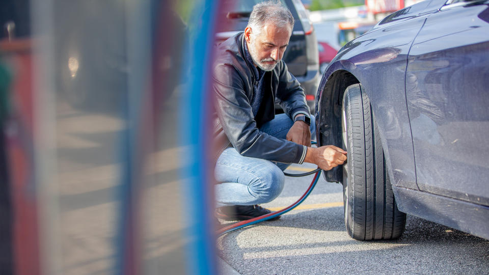 Mature Man Inflating Car Tires.