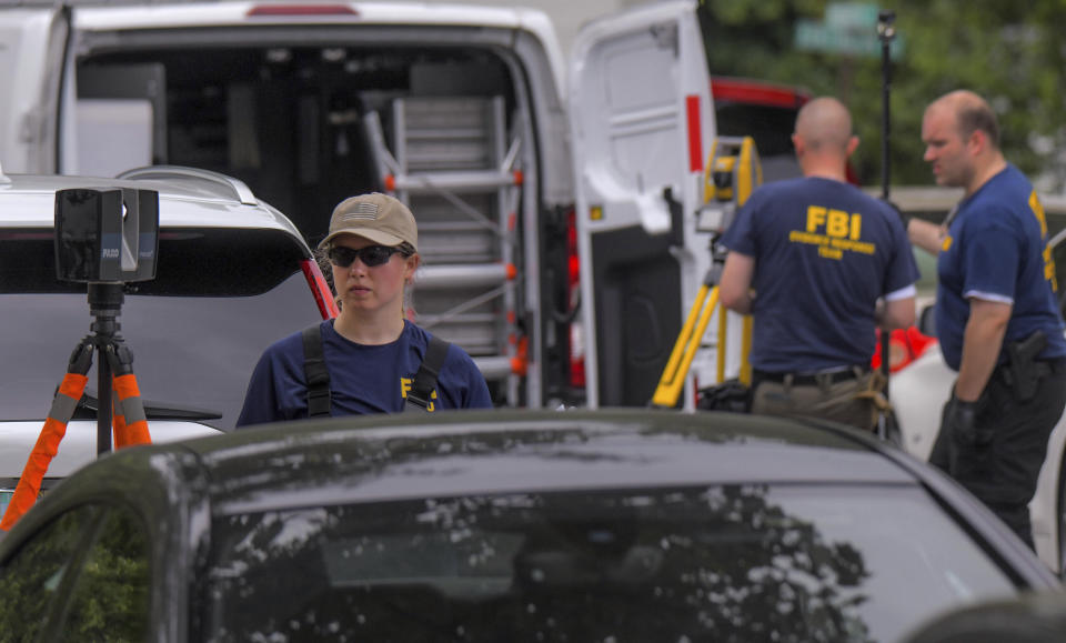 Members of the FBI Evidence Response Team use measuring devices to document the crime scene as Annapolis Police and other law enforcement officials gather evidence on Monday, June, 12, 2023, in Annapolis, Md., after a shooting on Sunday that left three people dead. (Karl Merton Ferron/The Baltimore Sun via AP)
