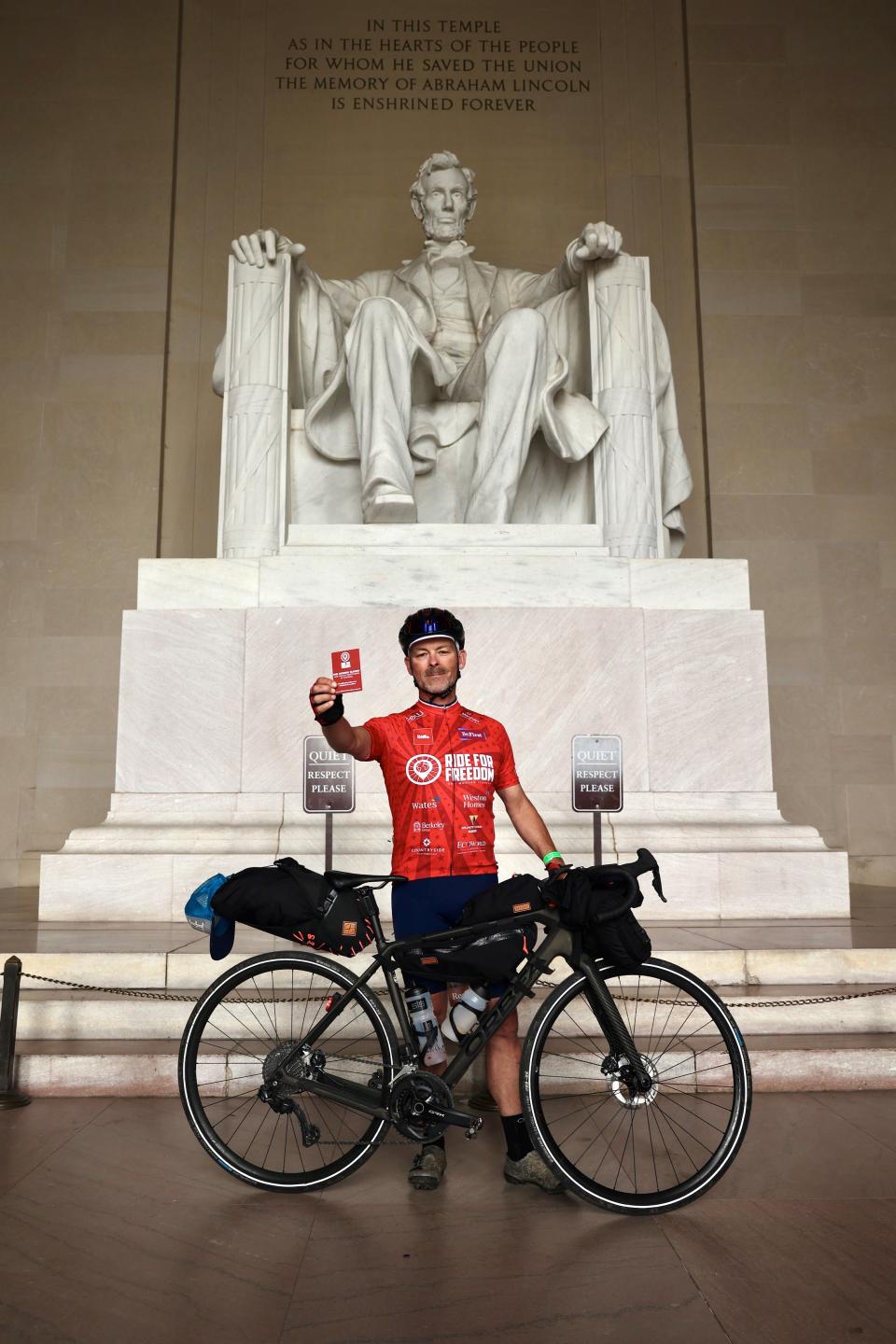 Man standing behind a bike with a card in his hand