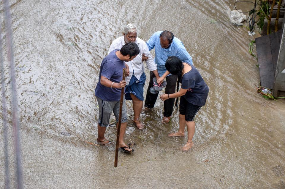 Residents help an elderly man (2L) to make his way on a flooded street following heavy rains in Hyderabad on October 14, 2020. (Photo by NOAH SEELAM / AFP) (Photo by NOAH SEELAM/AFP via Getty Images)