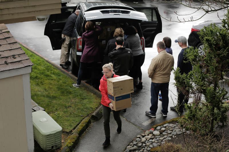 People load personal protective equipment and other supplies into a side entrance of the Life Care Center of Kirkland, the long-term care facility linked to several confirmed coronavirus cases in the state, in Kirkland