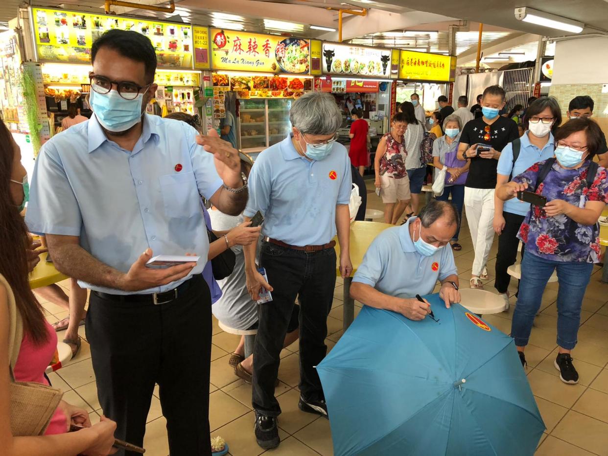 Workers' Party's secretary-general Pritam Singh (left) chats with residents during a party walkabout at the Kovan Market and Food Centre. Former party chief Low Thia Khiang (seated) was also present. (PHOTO: Nicholas Yong/Yahoo News Singapore)