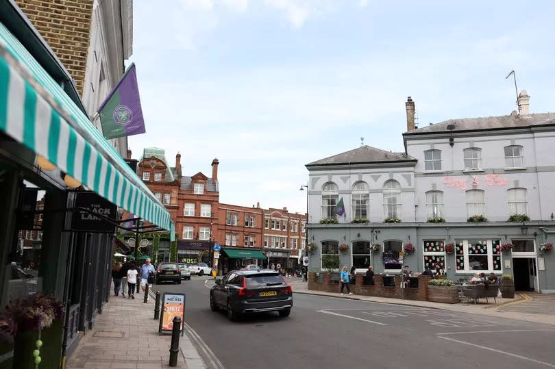 A car drives down a street in Wimbledon Village