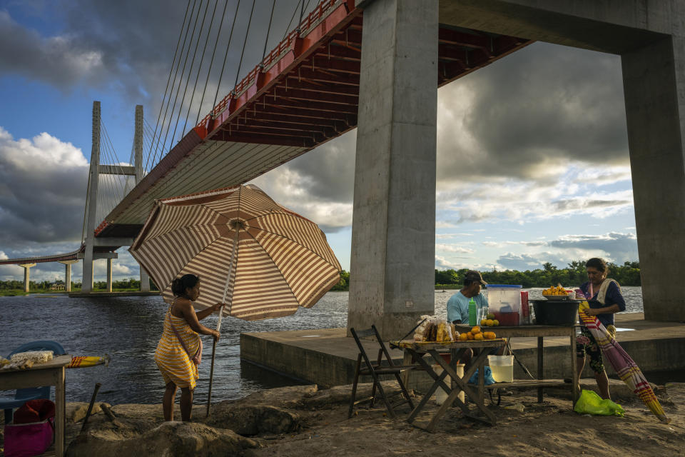 Vendedores colocan puestos de comida bajo un puente que forma parte de un proyecto federal de carreteras que pasa sobre el río Nanay, en Iquitos, Perú, el lunes 27 de mayo de 2024. (AP Foto/Rodrigo Abd)