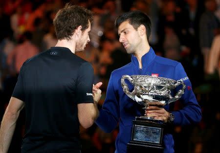 Serbia's Novak Djokovic (R) shakes hands with Britain's Andy Murray while holding the men's singles trophy after winning their final match at the Australian Open tennis tournament at Melbourne Park, Australia, January 31, 2016. REUTERS/Thomas Peter