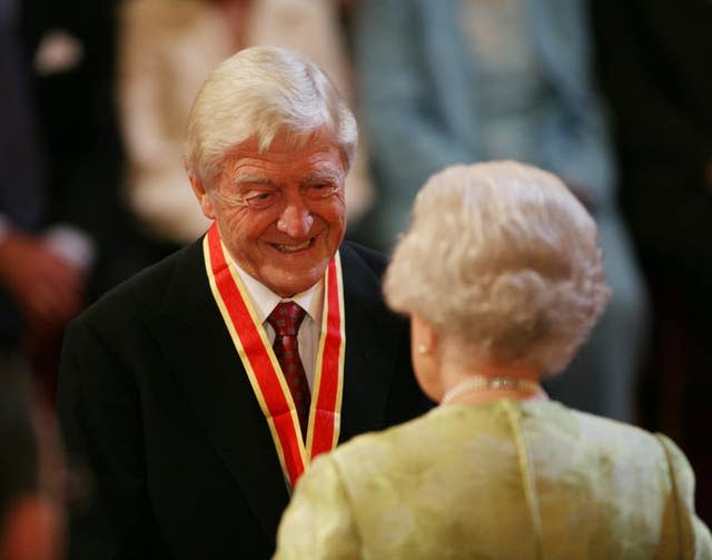 Sir Michael Parkinson receives his knighthood from the Queen