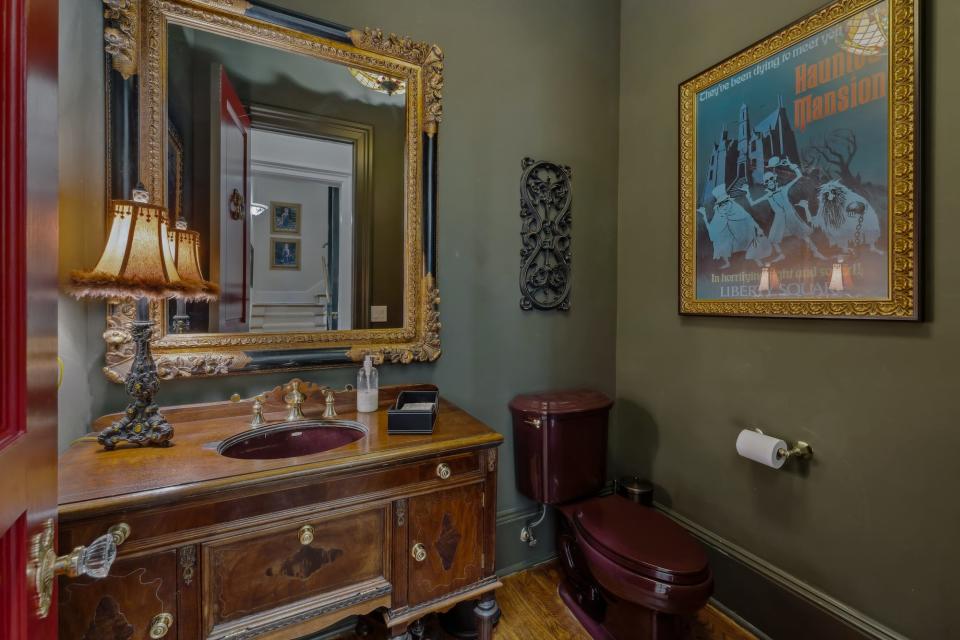 A dark green bathroom with a "Haunted Mansion" poster.