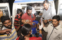 In this Friday, Dec. 14, 2018 photo, an Indian girl is brought for treatment after a case of suspected food poisoning, at a hospital in Mysore, Karnataka state, India. Police on Saturday arrested three people after at least 10 died of suspected food poisoning following a ceremony to celebrate the construction of a new Hindu temple in southern India. (AP Photo/Madhusudhan Sr)