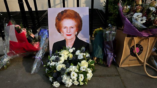 A portrait of former Prime Minister Margaret Thatcher is left next to floral tributes outside her residence in Chester Square.