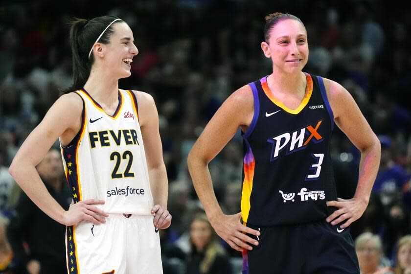 Caitlin Clark and Diana Taurasi hold their hands on their hips while laughing on court