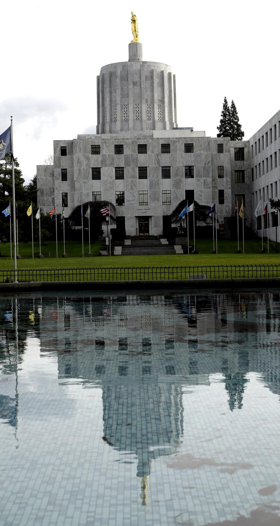 FILE - In this Feb. 2, 2015, file photo, the Capitol building is reflected in a pond on the Capitol grounds in Salem, Ore. The U.S. Army Corps of Engineers has determined that a large earthquake could cause the spillway gates of a dam in Oregon to buckle, resulting "in a potentially catastrophic flood." Hundreds of thousands of people, including those in the state capital of Salem, live downstream of the Detroit Dam. The Corps announced late Monday, March 15, 2021 it will try to minimize the danger by reducing the maximum height of the lake by five feet starting in April. (AP Photo/Don Ryan, File)