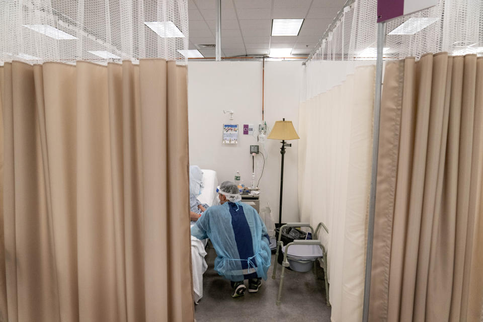 FILE - A physical therapist works with a patient at a field hospital operated by Care New England set up in a former bank call center to handle a surge of COVID-19 patients in Cranston, R.I, Dec. 14, 2020. Roughly 84 million people are covered by Medicaid, the government-sponsored program that's grown by 20 million people since January 2020, just before the coronavirus pandemic hit. Now, as states begin checking everyone’s eligibility for Medicaid for the first time in three years, as many as 14 million people could lose access to that coverage. (AP Photo/David Goldman, File)